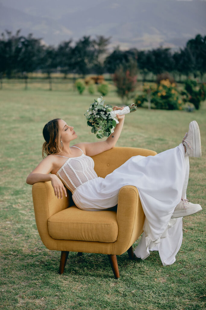 mujer con vestido de novia sentada en un sofa amarillo con un lindo buqué en subachoque Colombia